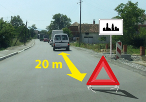 Slika uz pitanje: U situaciji prikazanoj na slici kolona zaustavljenih motornih vozila na putu u naselju