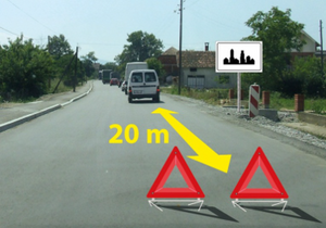 Slika uz pitanje: U situaciji prikazanoj na slici kolona zaustavljenih motornih vozila na putu u naselju