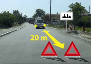 Slika uz pitanje: U situaciji prikazanoj na slici kolona zaustavljenih motornih vozila na putu u naselju